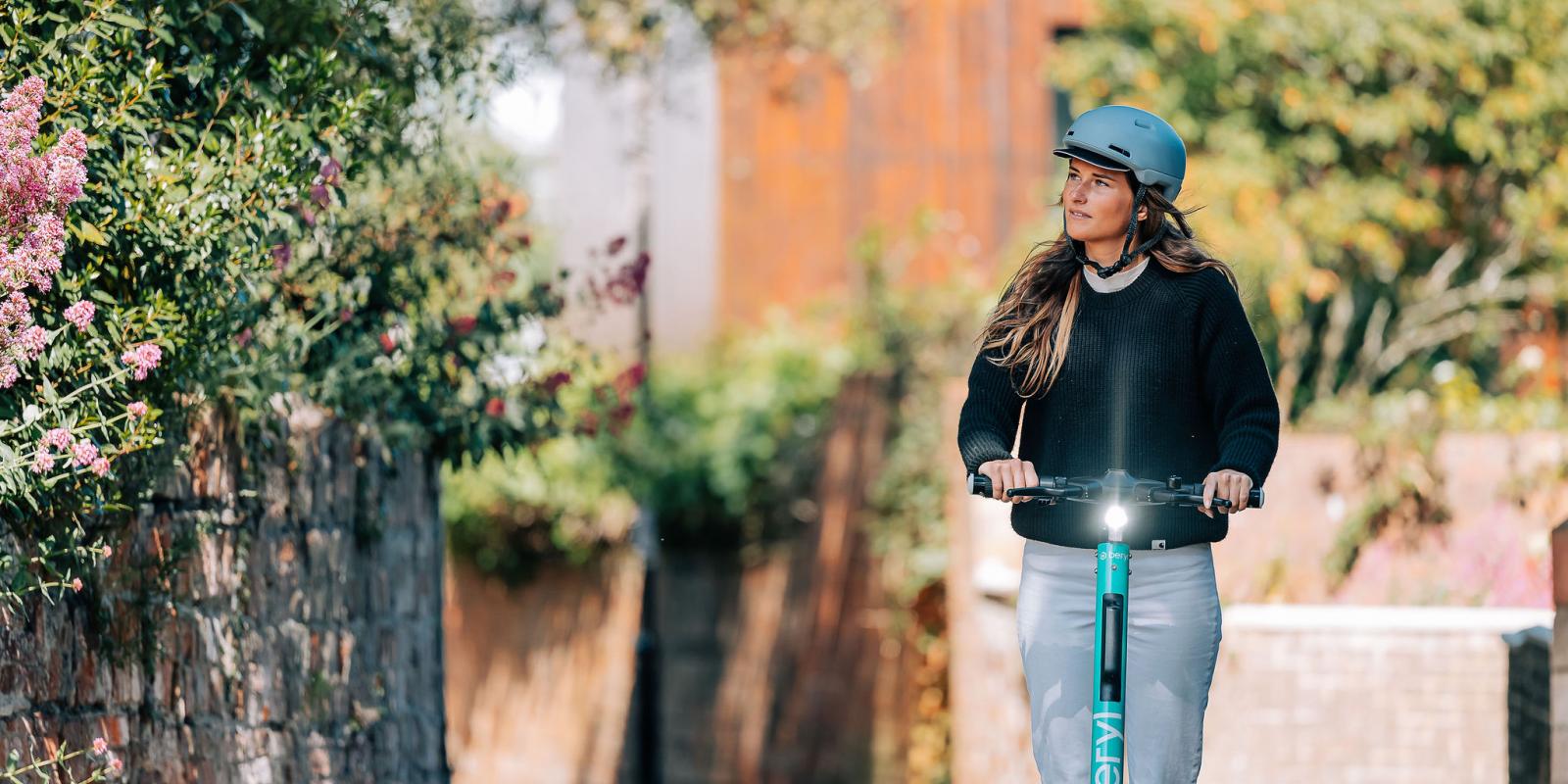 woman wearing helmet riding Beryl scooter