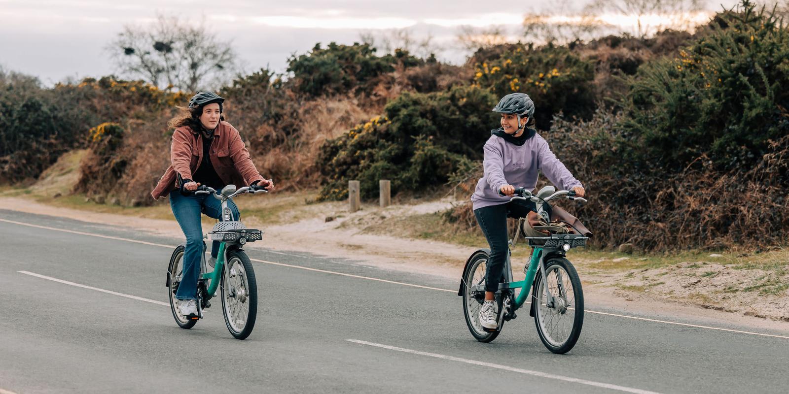 Two women riding Beryl bikes in Studland