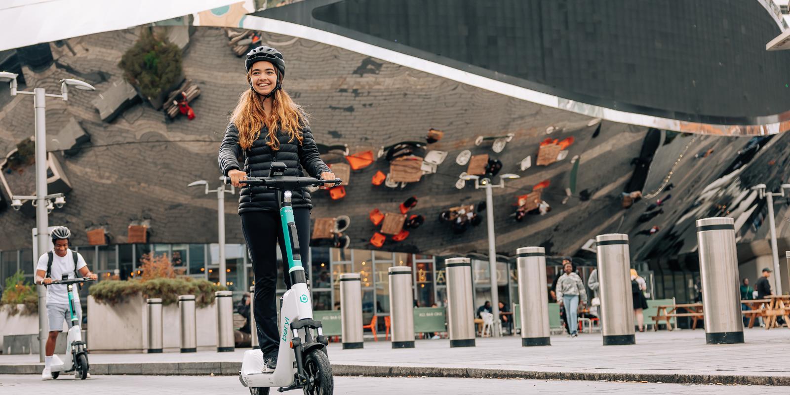 Man and woman riding Beryl e-scooters in front of the Bullring in Birmingham