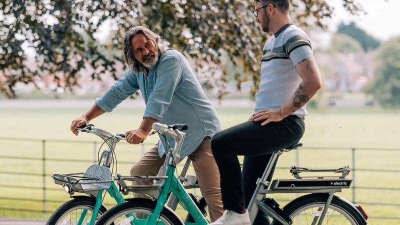 Two men on beryl bikes in the park
