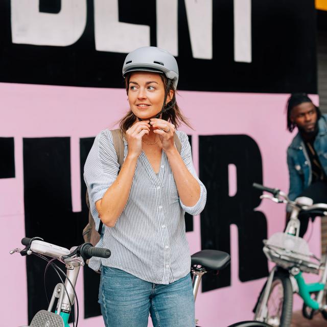 Woman fastening bike helmet to ride a Beryl Bike