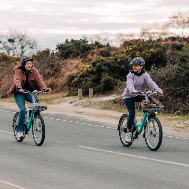 Two women riding Beryl bikes in Studland