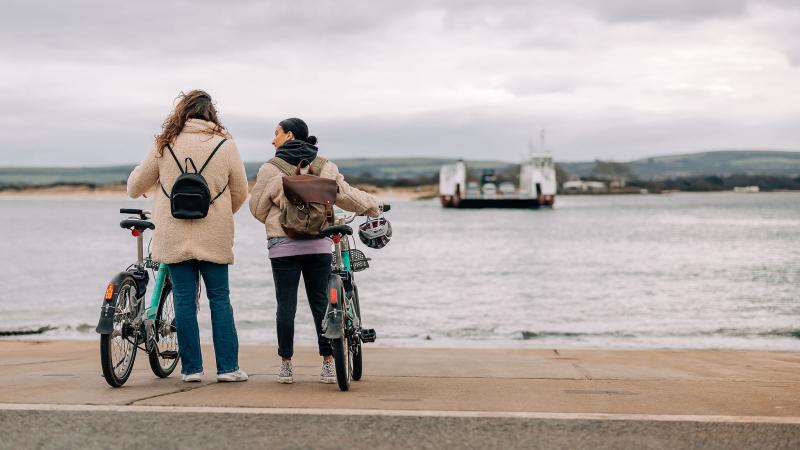 two women with Beryl bikes looking at the Studland chain ferry